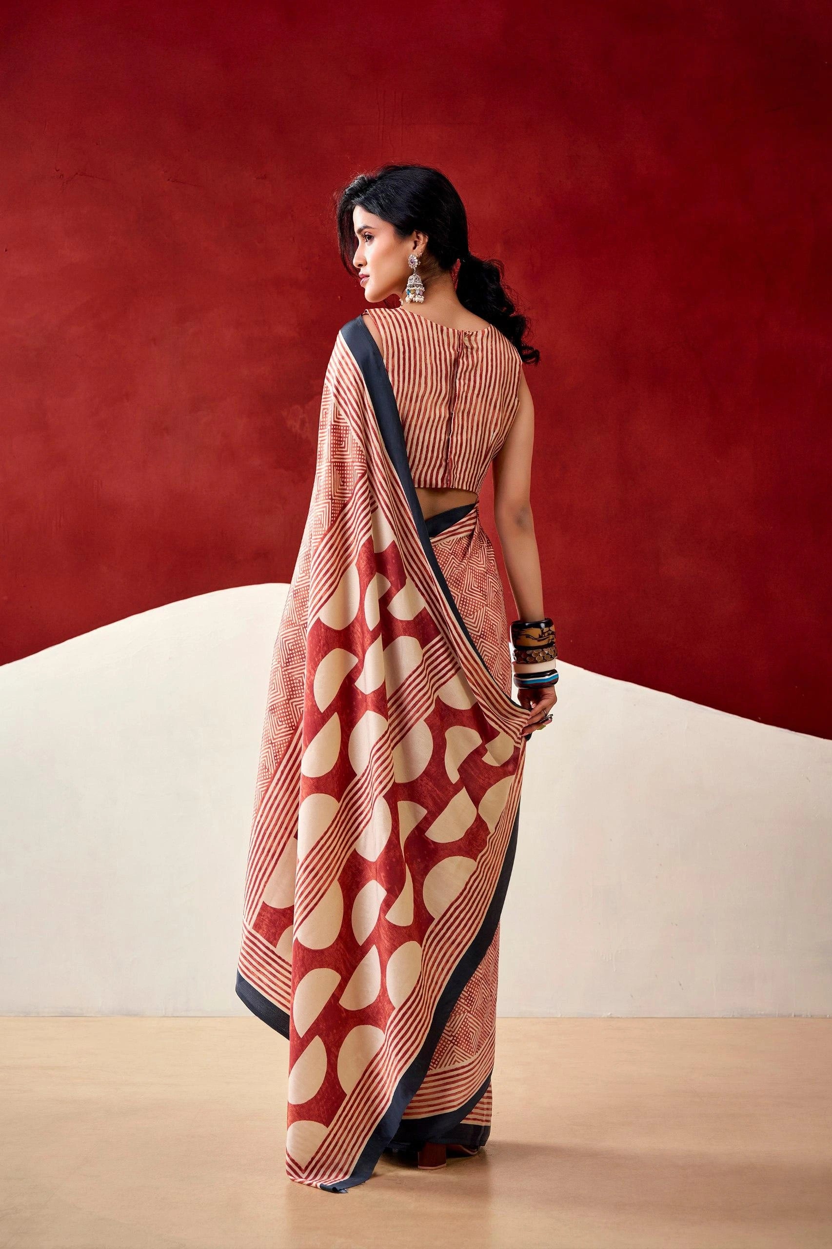 Woman wearing a red and white patterned saree against a red background